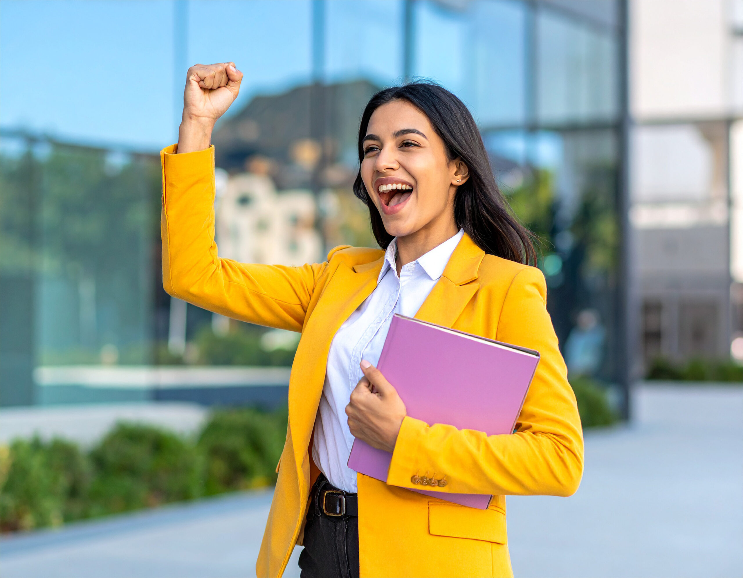 Junge Frau mit Gewinnerpose und glücklichem Ausdruck, die mit Leistung zu Erfolg führt.